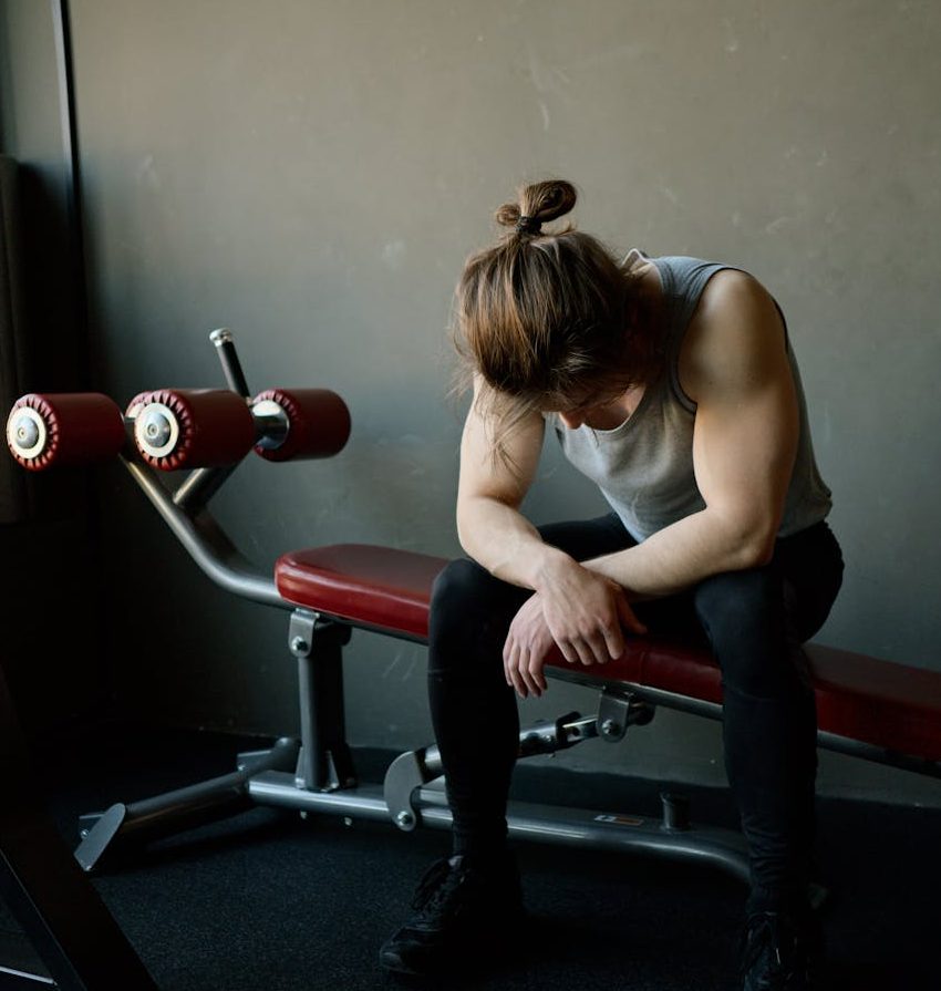 A woman looks depleted and tired after completing her exercise set. One wonders if she is tired from exercise, overall exhaustion or from sleep deprivation.