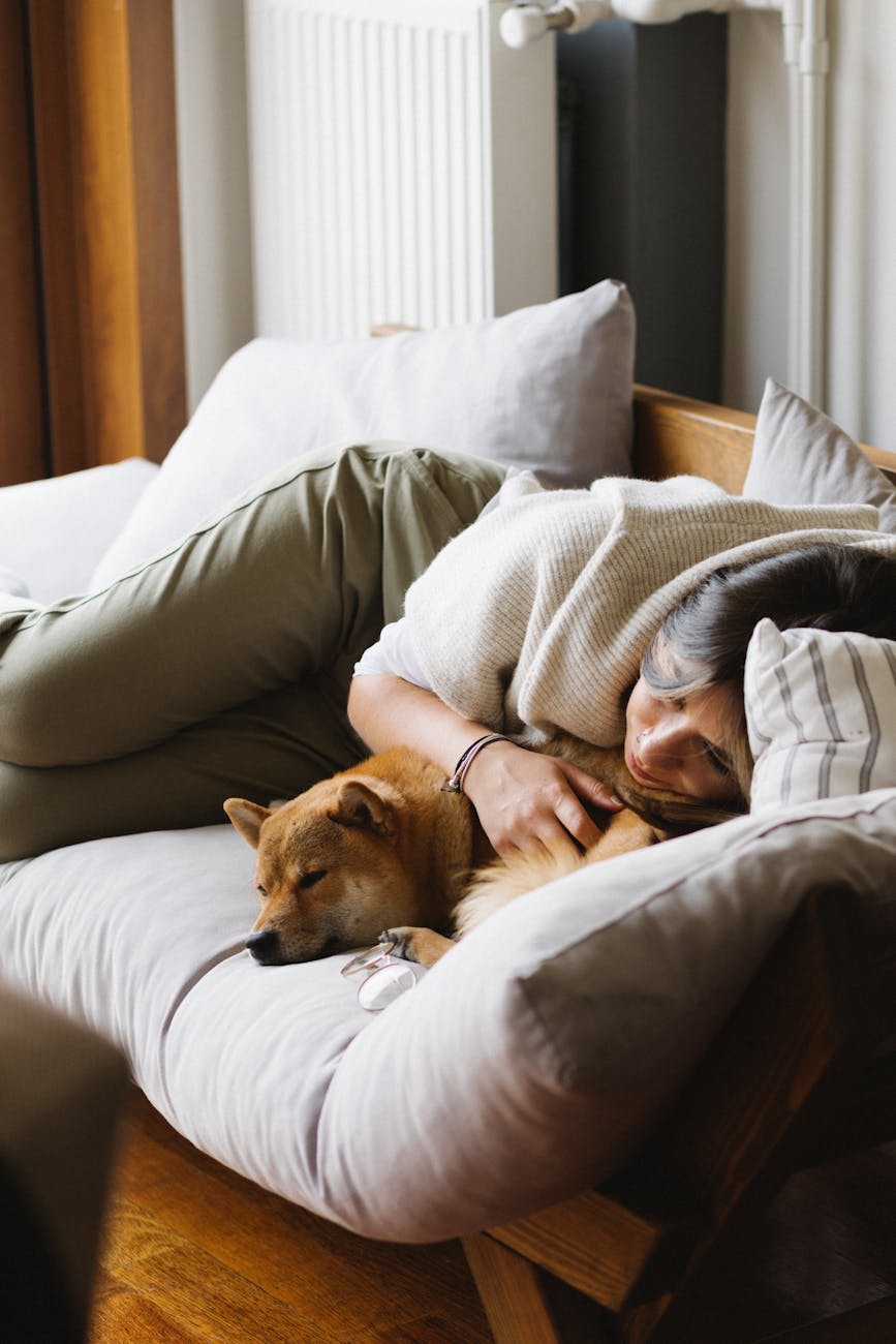 Image of woman taking a daytime time on her couch with her dog.